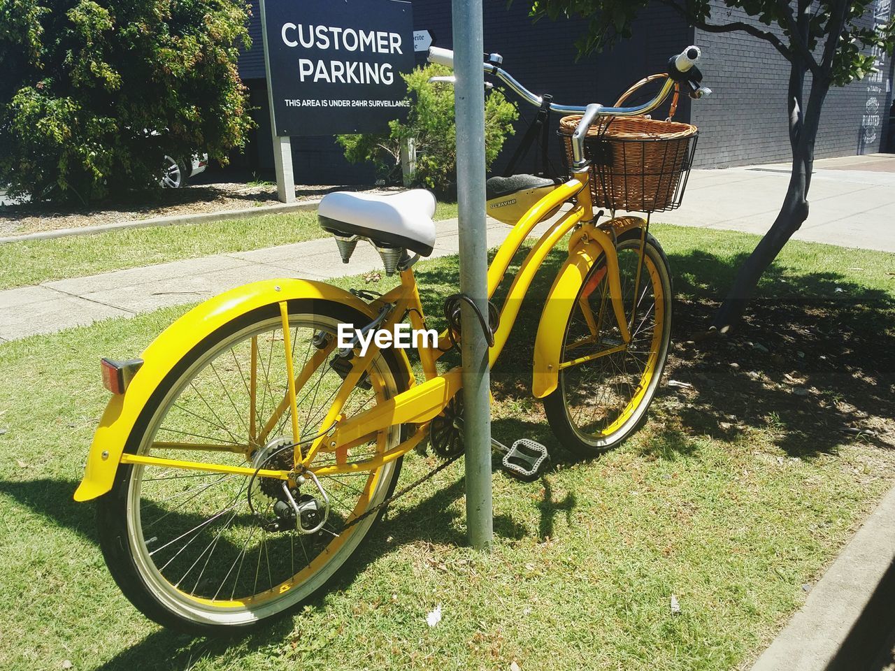 Yellow bicycle locked to metal pole