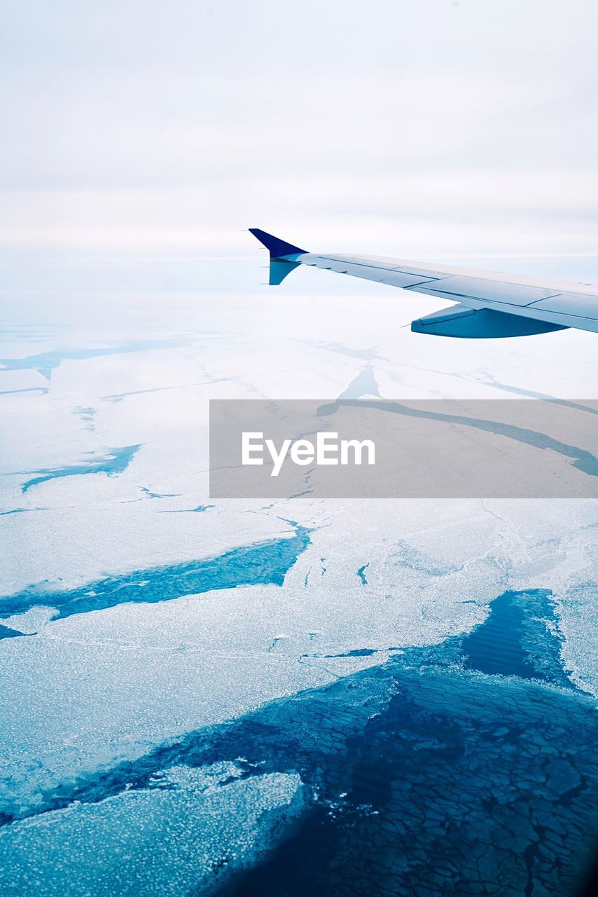 Close-up of airplane wing over sea during winter