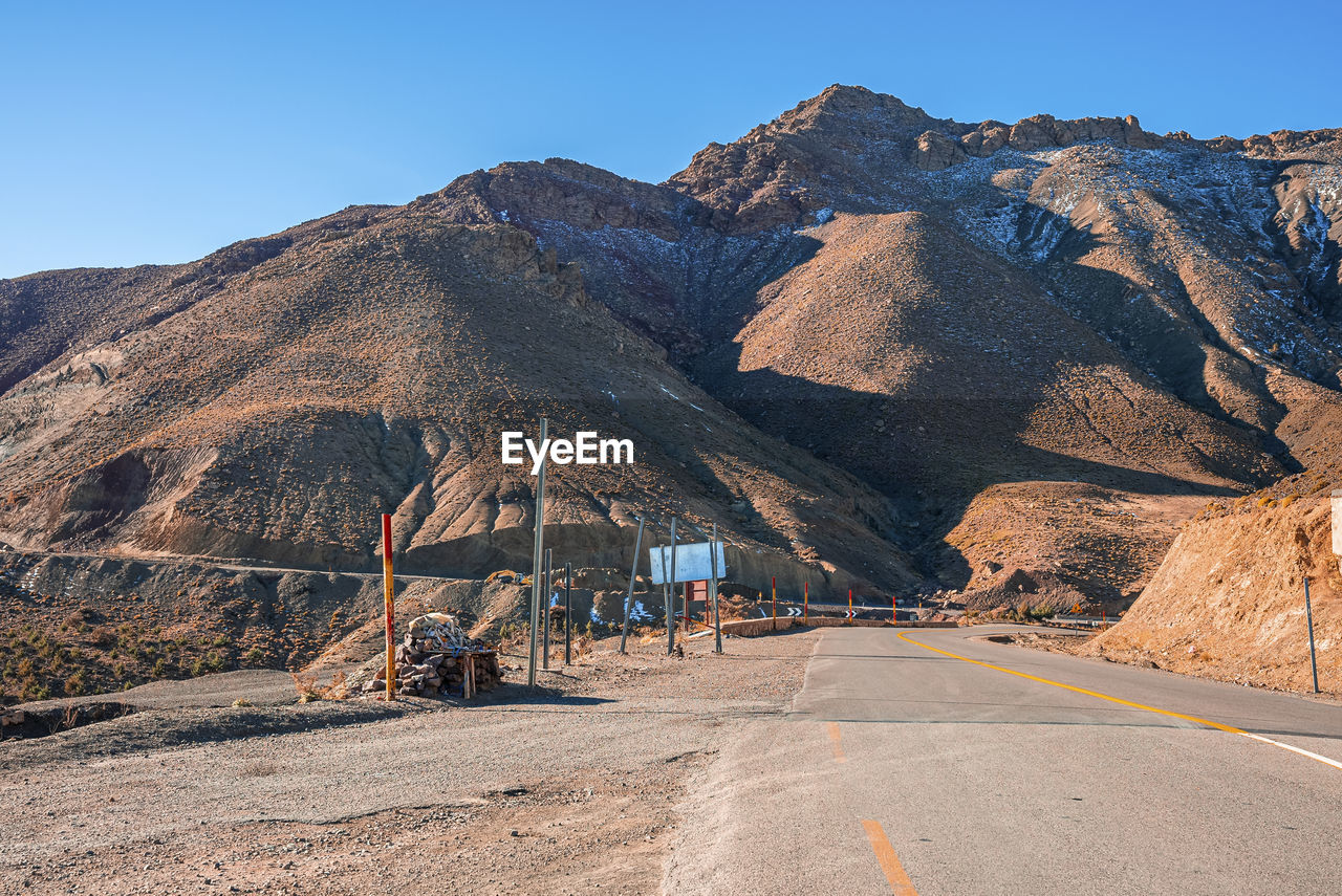 Empty asphalt curvy road through mountains in sunny summer day