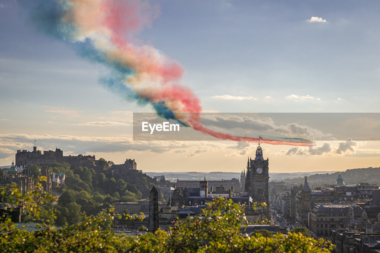 Red arrows flypast over edinburgh city in scotland at sunset.