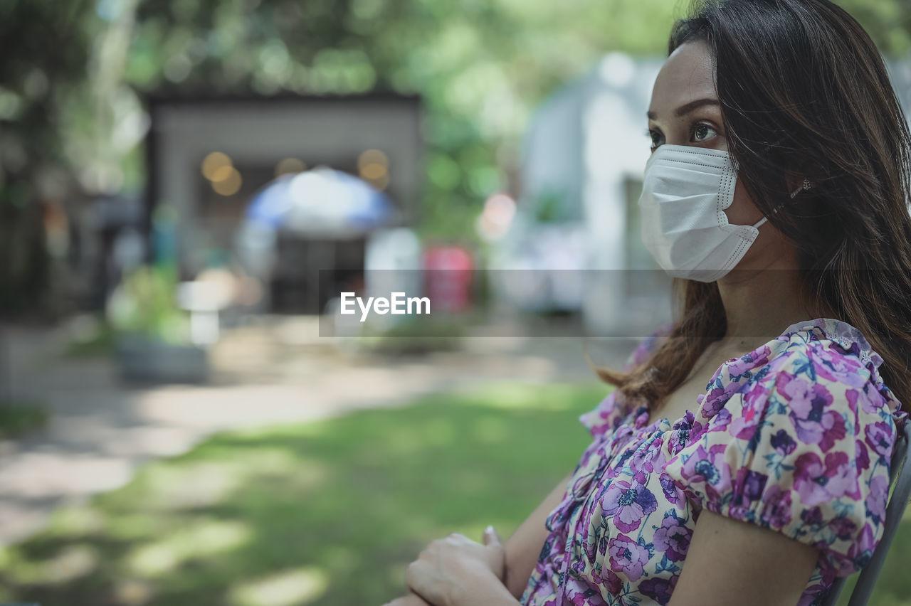 Young woman in daydream emotion , outdoor with surgical protection mask