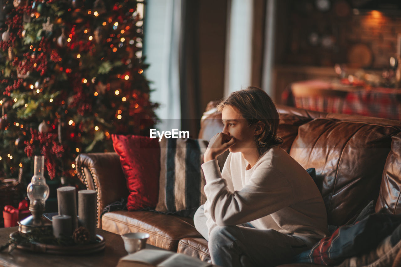 Portrait of candid authentic smiling boy teenager having fun emotion at wooden lodge xmas decorated