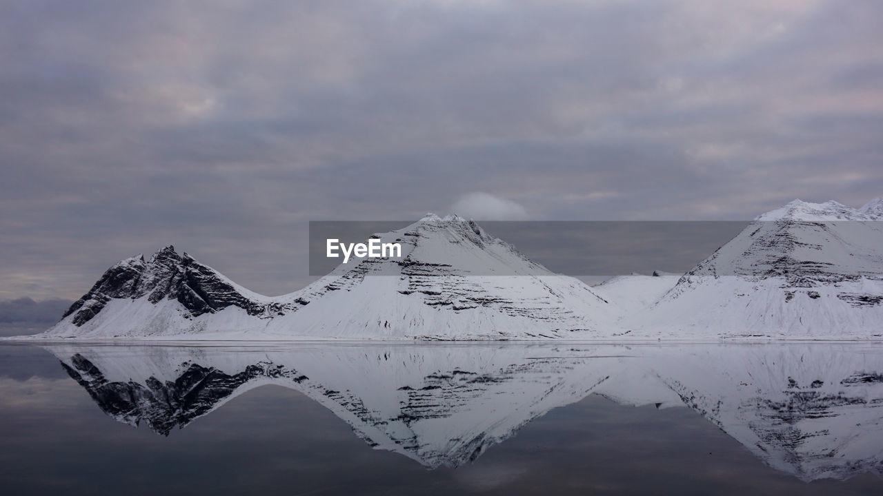 Scenic view of lake by snowcapped mountains against sky