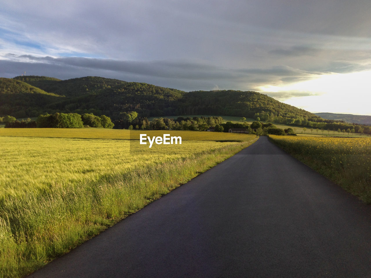 View of country road against cloudy sky