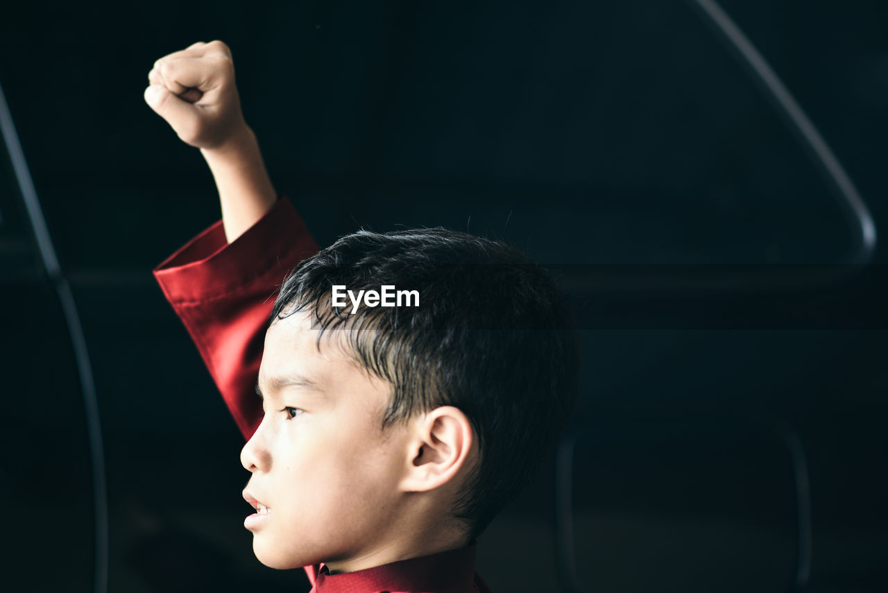 Close-up of boy with hand raised