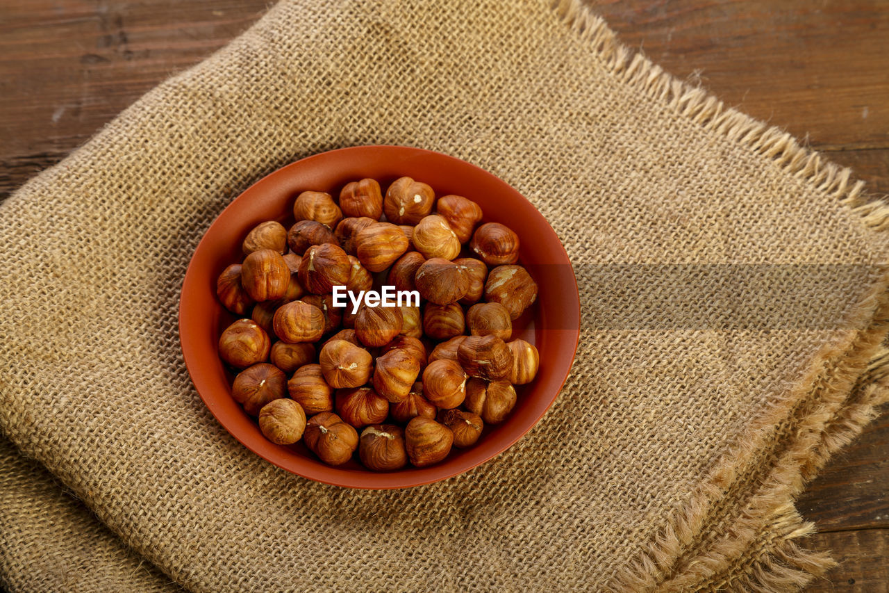 Hazelnuts in a clay plate on burlap on a wooden table. horizontal photo