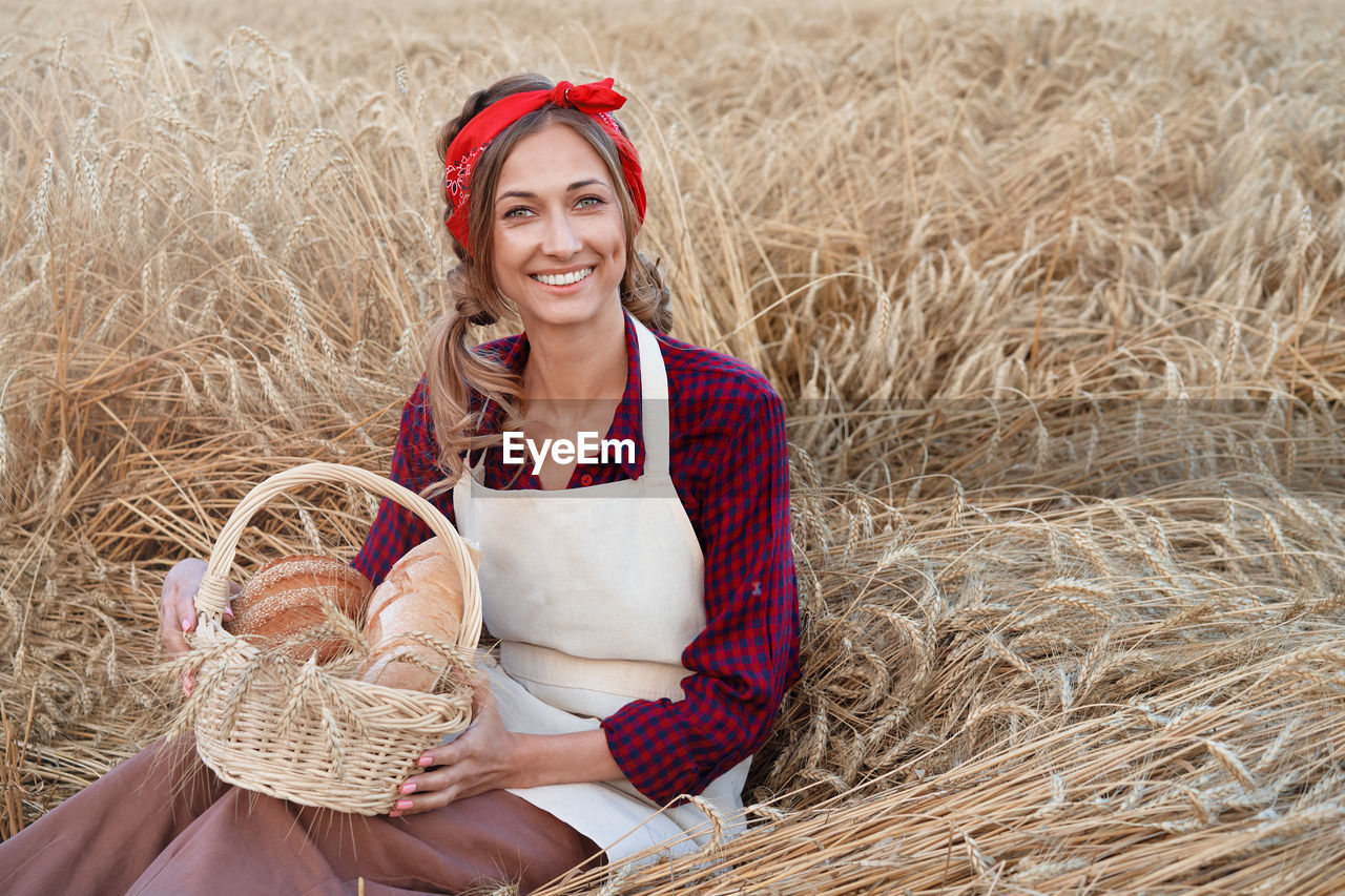 PORTRAIT OF A SMILING YOUNG WOMAN HOLDING HAY