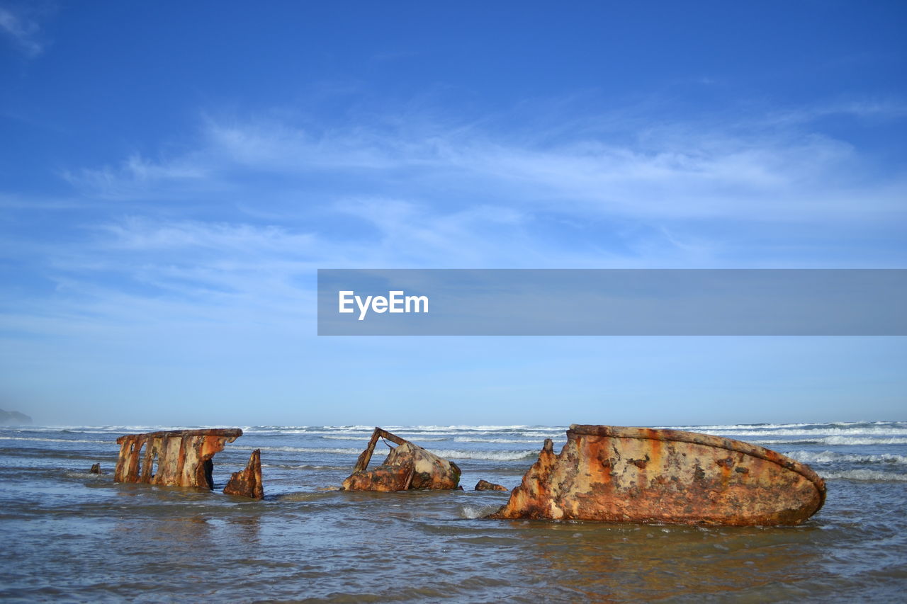 Shipwreck at beach against sky