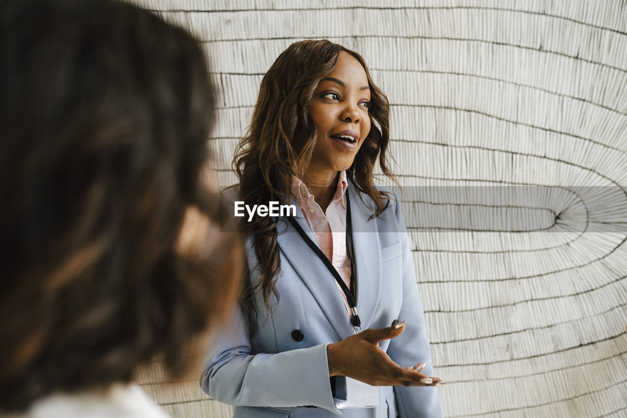 Female professional gesturing while discussing with colleagues during networking event