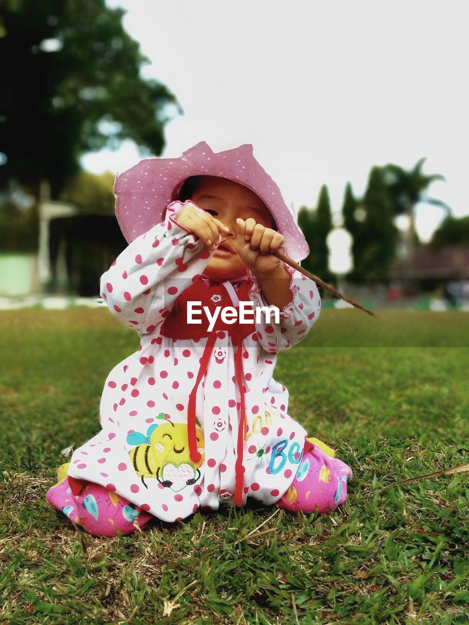 Cute baby girl sitting on grass in field