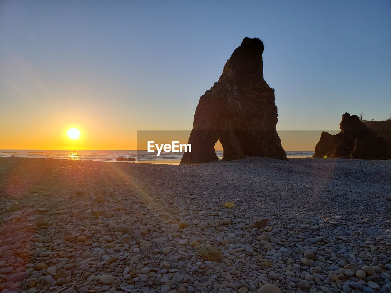 Rock formation on beach against sky during sunset