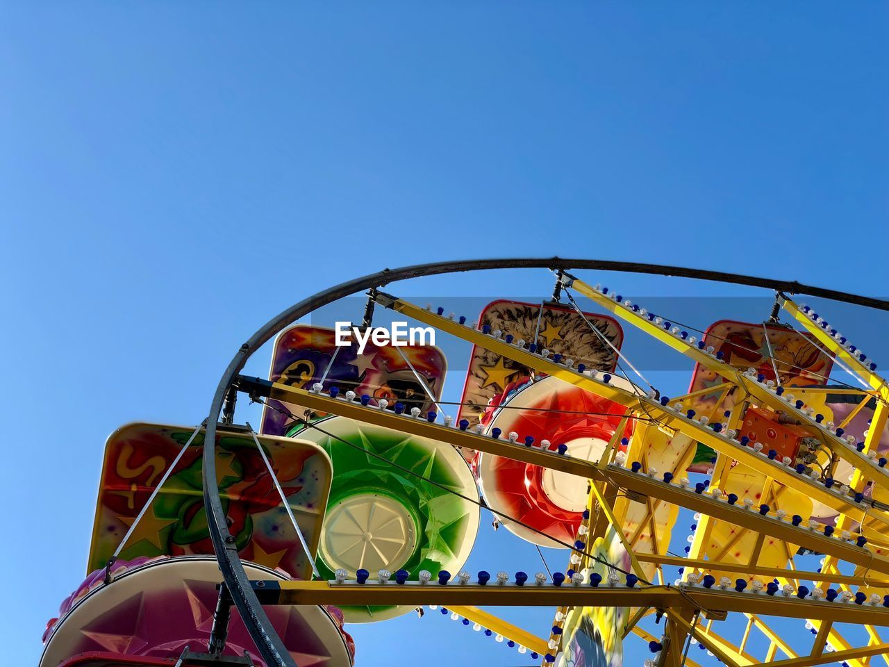 Low angle view of ferris wheel against clear blue sky