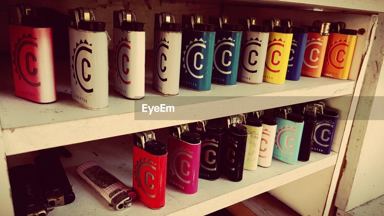 CLOSE-UP OF MULTI COLORED BOTTLES ON SHELF AT RACK