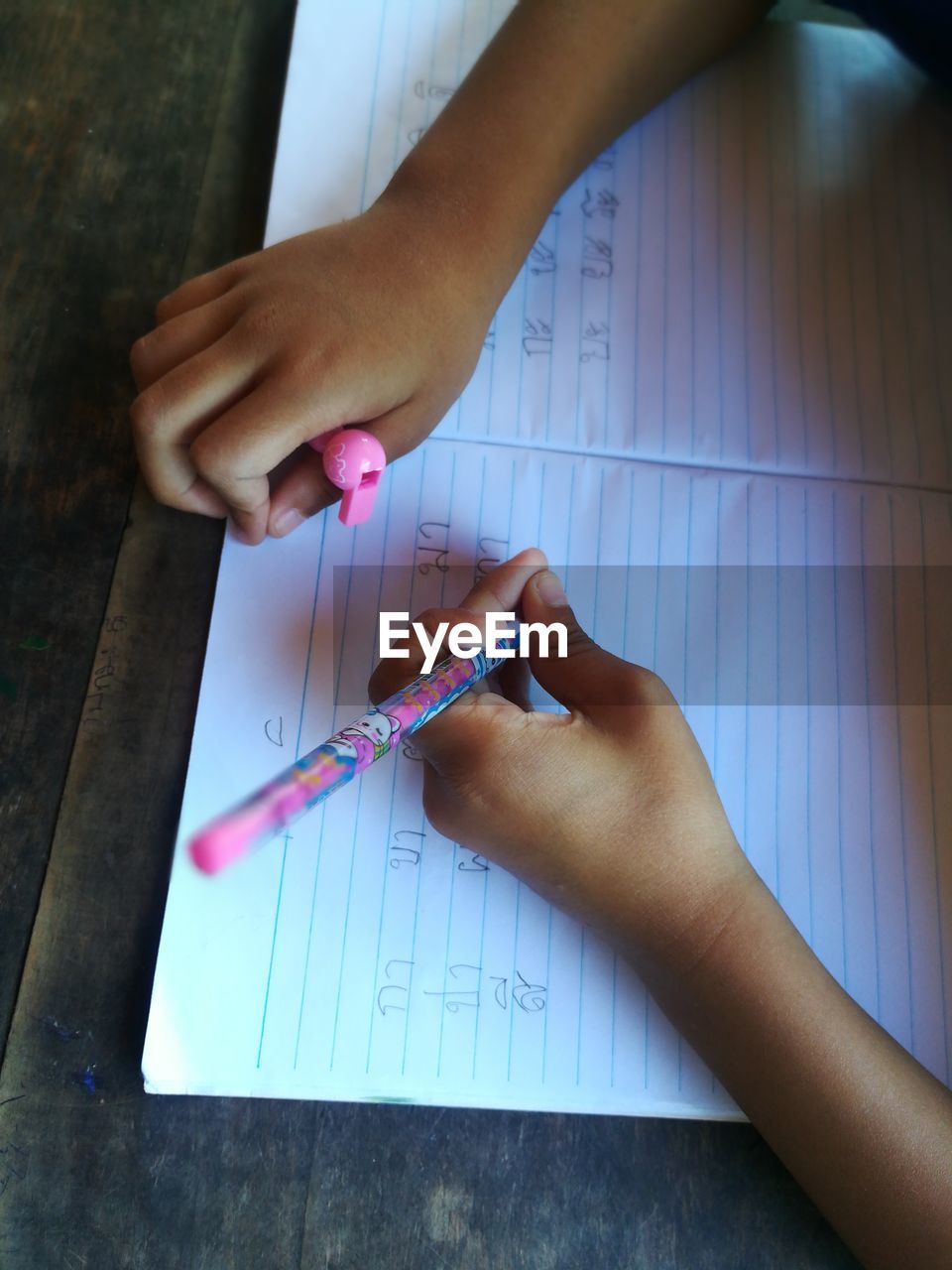 Cropped hands of boy writing in book