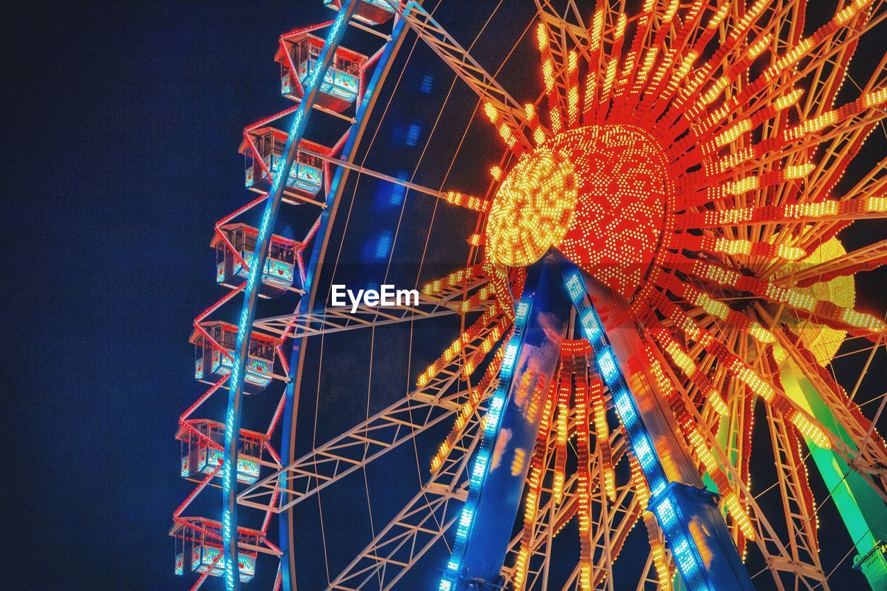 Low angle view of illuminated ferris wheel against sky at night