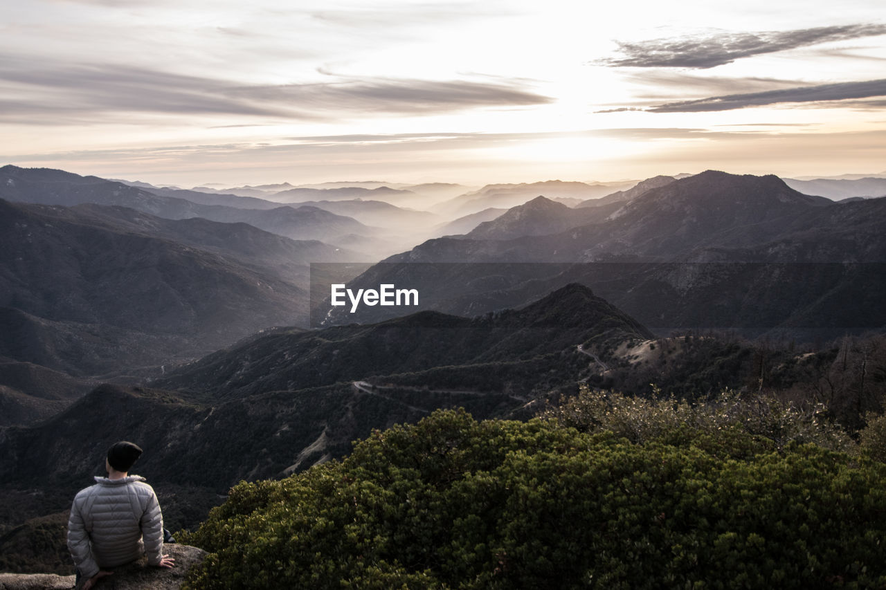 Rear view of man standing on mountain against sky