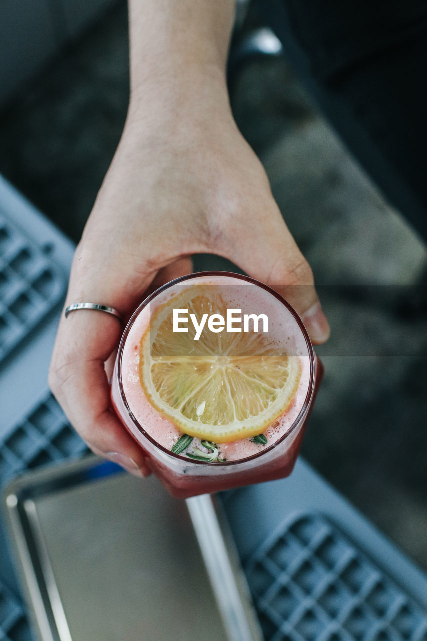 HIGH ANGLE VIEW OF HAND HOLDING LEMON SLICE