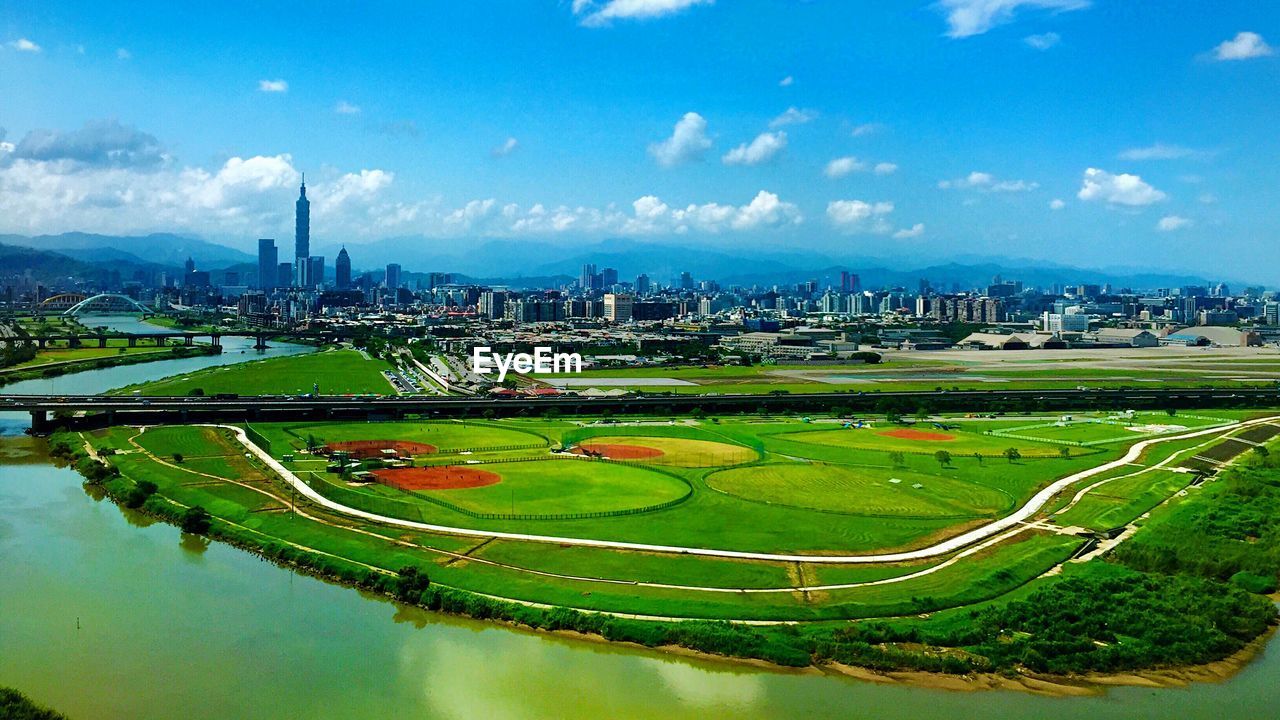 High angle view of green field by river in city