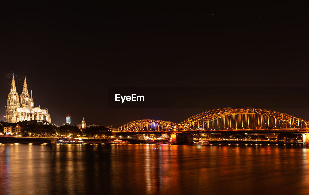 Illuminated bridge over river at night