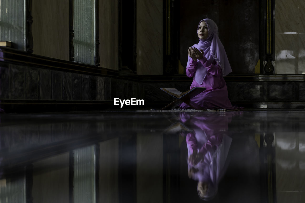 WOMAN STANDING AGAINST PINK WATER AND REFLECTION