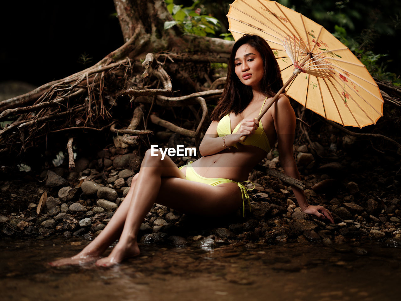 Portraiture shot of a beautiful asian female model in bikini at a river