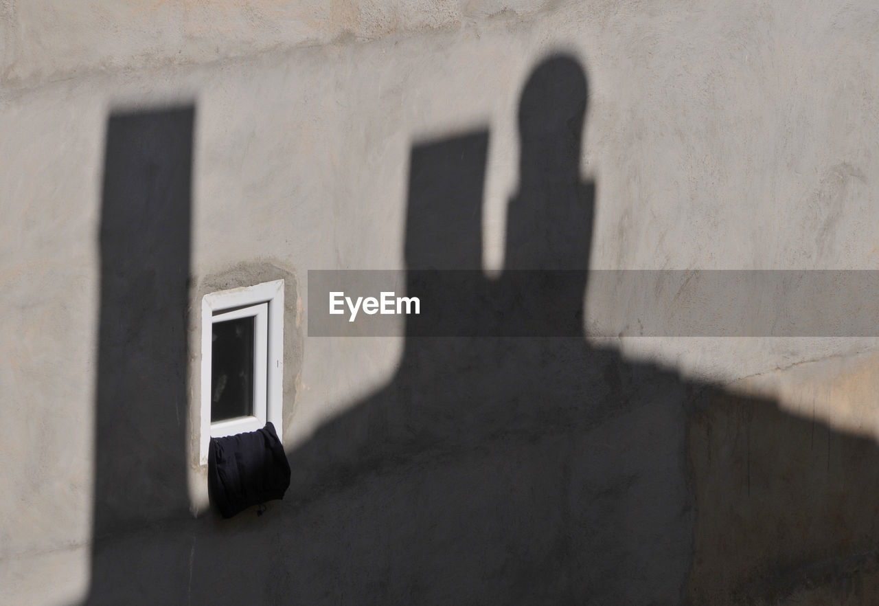 SHADOW OF PERSON ON WALL AGAINST BUILDING