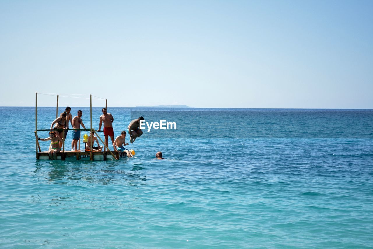 People at diving platform amidst sea