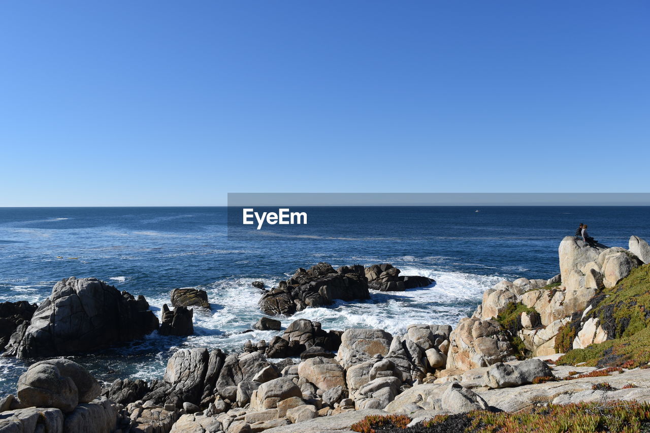 ROCKS IN SEA AGAINST CLEAR BLUE SKY