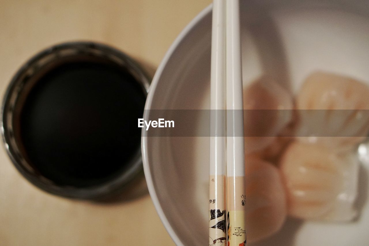 Directly above view of chinese dumplings in bowl with chopsticks and sauce on table