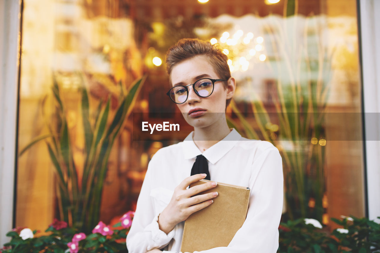 PORTRAIT OF YOUNG MAN WITH EYEGLASSES ON ILLUMINATED PLANT