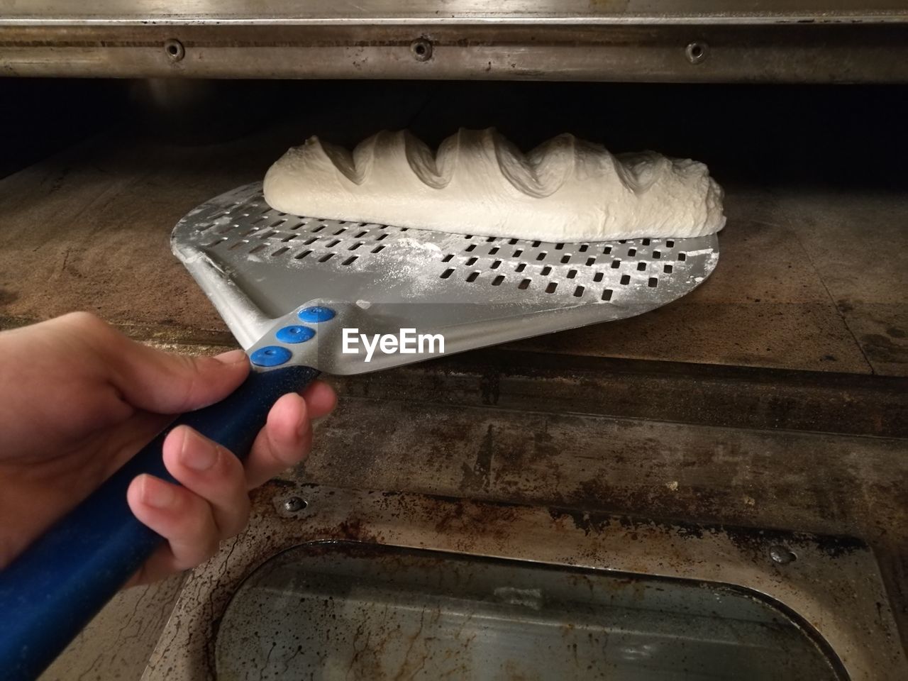 Cropped hand putting bread in oven