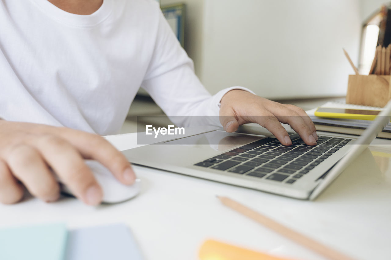 MIDSECTION OF MAN USING LAPTOP