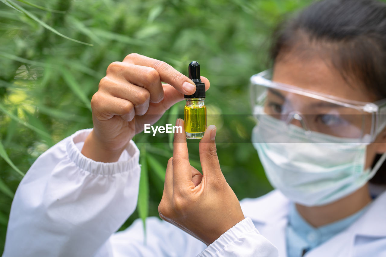 Woman holding essential oil bottle at green house