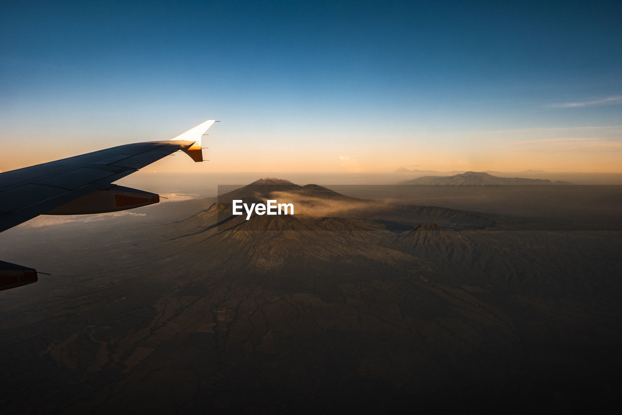 AIRPLANE FLYING OVER MOUNTAINS AGAINST SKY