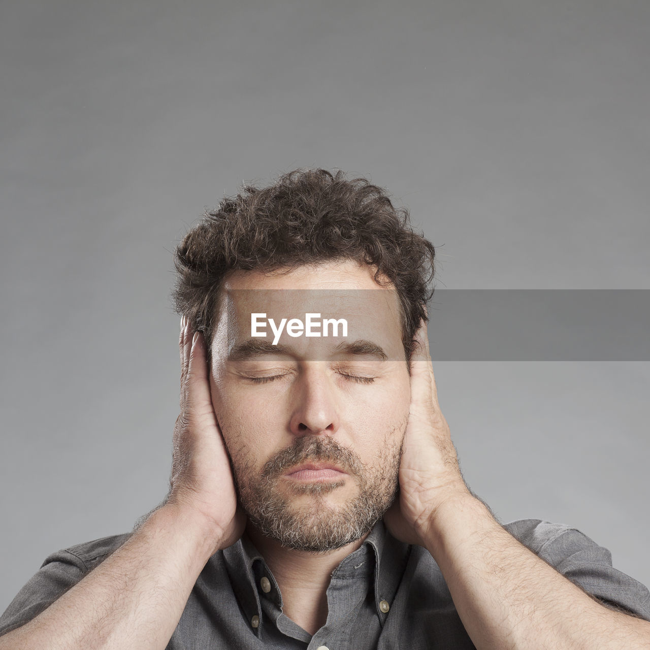 Man covering ears against white background