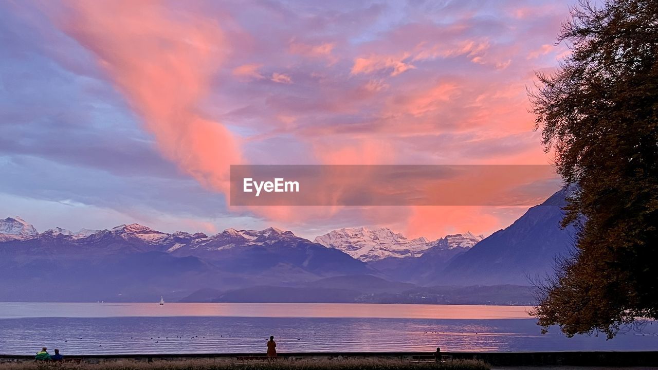 water, sky, mountain, beauty in nature, morning, scenics - nature, dawn, sunrise, sea, cloud, nature, environment, landscape, land, travel destinations, horizon, reflection, travel, mountain range, beach, tranquility, tree, tranquil scene, holiday, sunlight, outdoors, dramatic sky, vacation, trip, tourism, body of water, snow, sun, plant, cold temperature, idyllic, winter