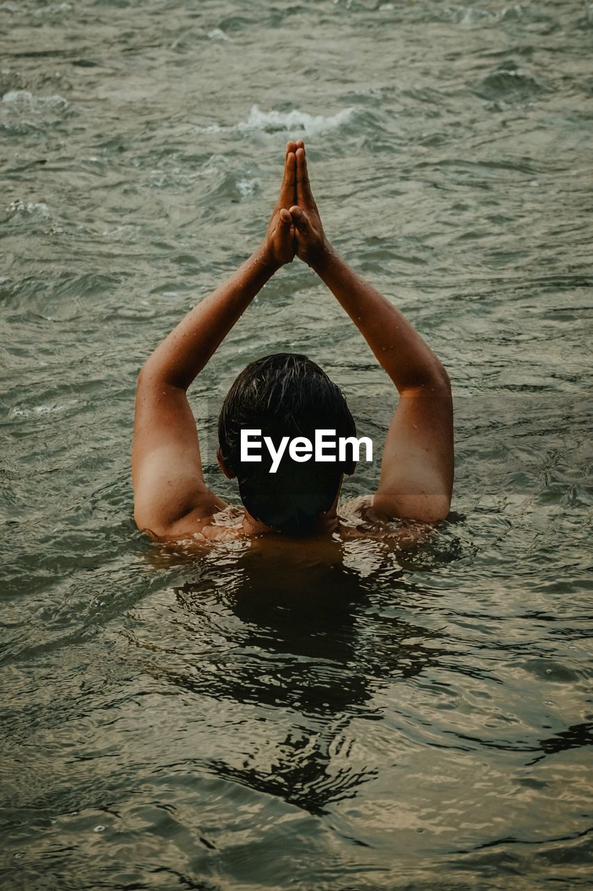 A man is seen from behind who is half submerged in the water