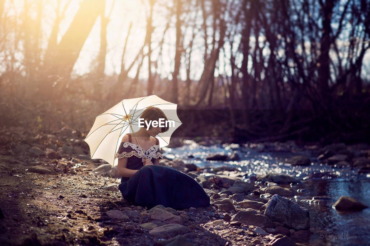 Woman sitting by stream in forest