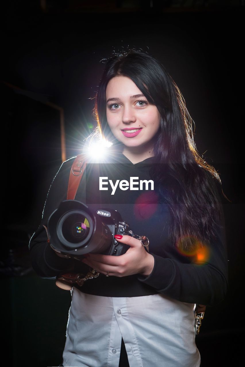 PORTRAIT OF SMILING YOUNG WOMAN PHOTOGRAPHING CAMERA