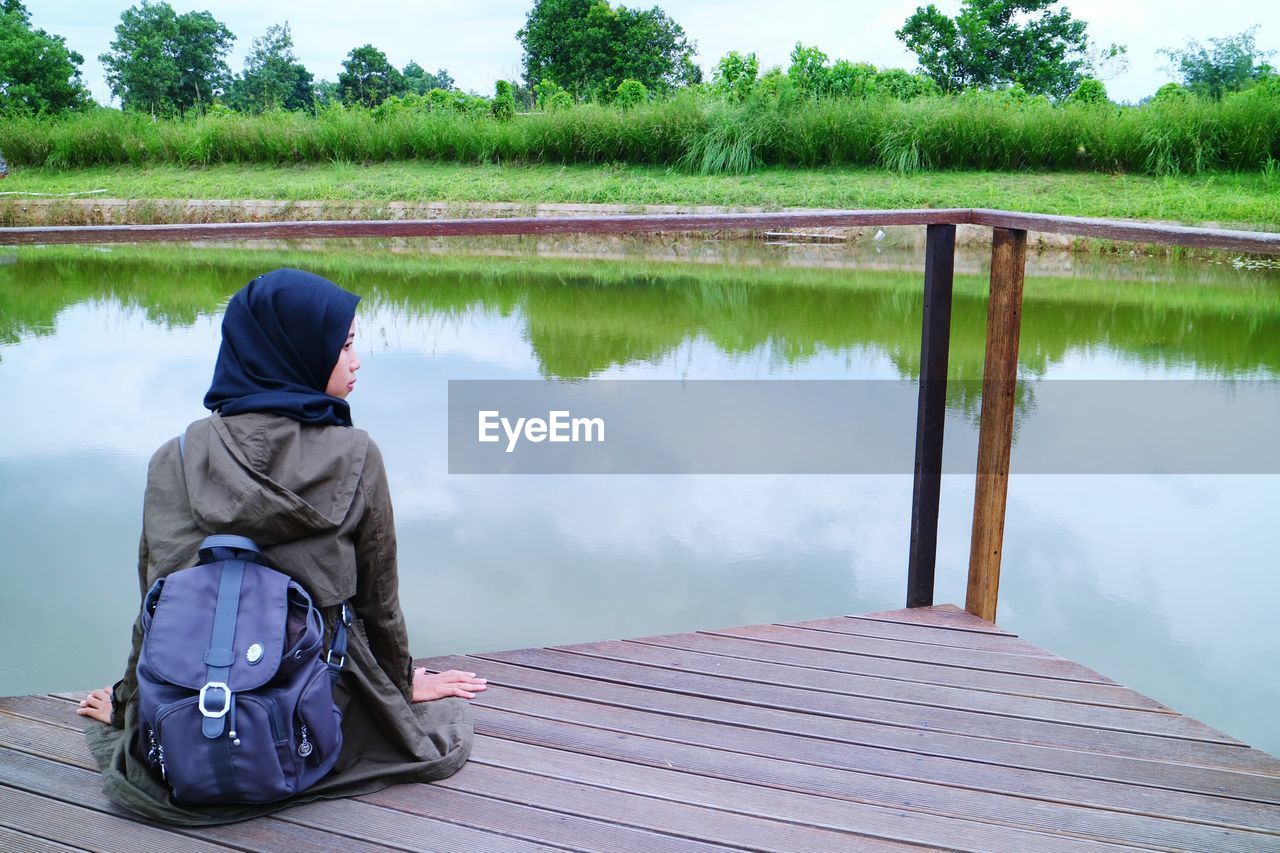 Rear view of girl sitting by lake