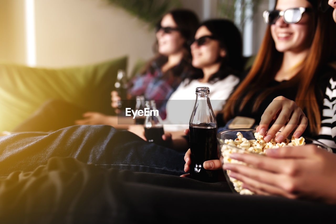 Group of people are watching a movie. friend girls eat popcorn and drink soda