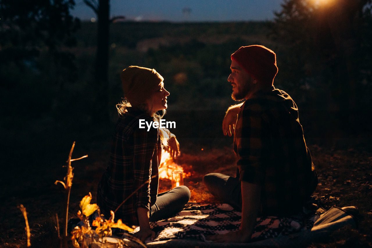 PANORAMIC VIEW OF PEOPLE SITTING ON BONFIRE