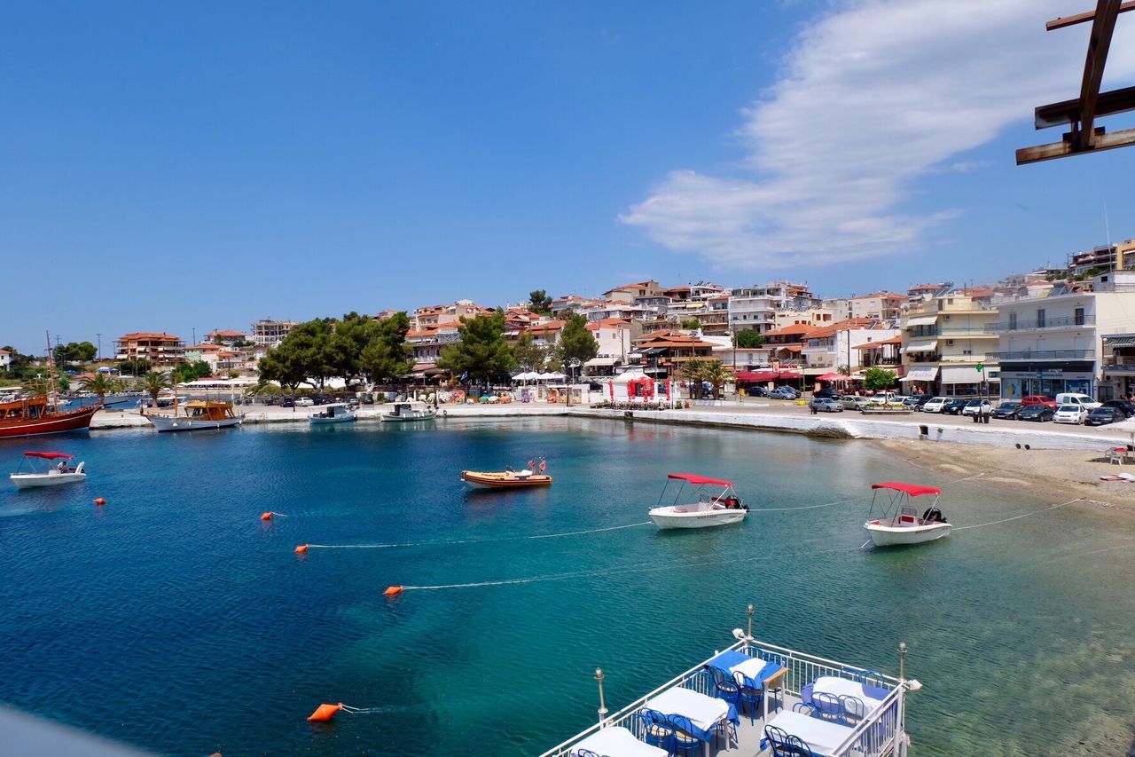 Boats on sea by city buildings against sky