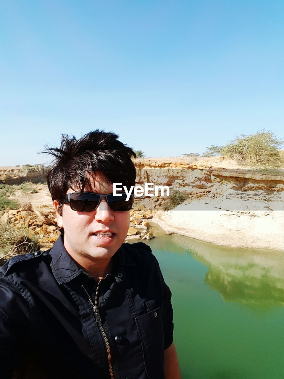 Portrait of man wearing sunglasses against lake