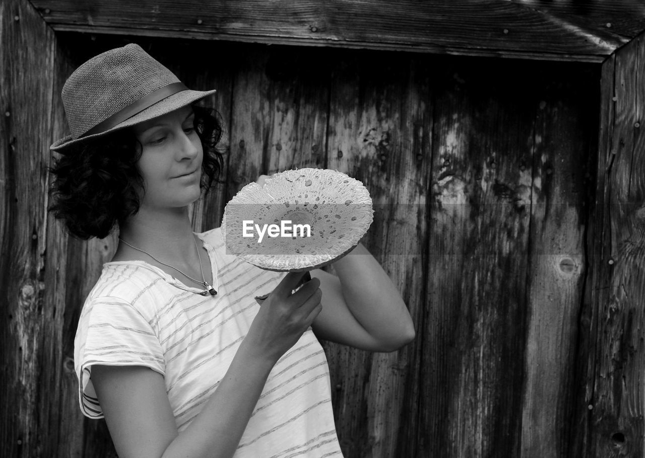 Woman holding mushroom while standing outdoors