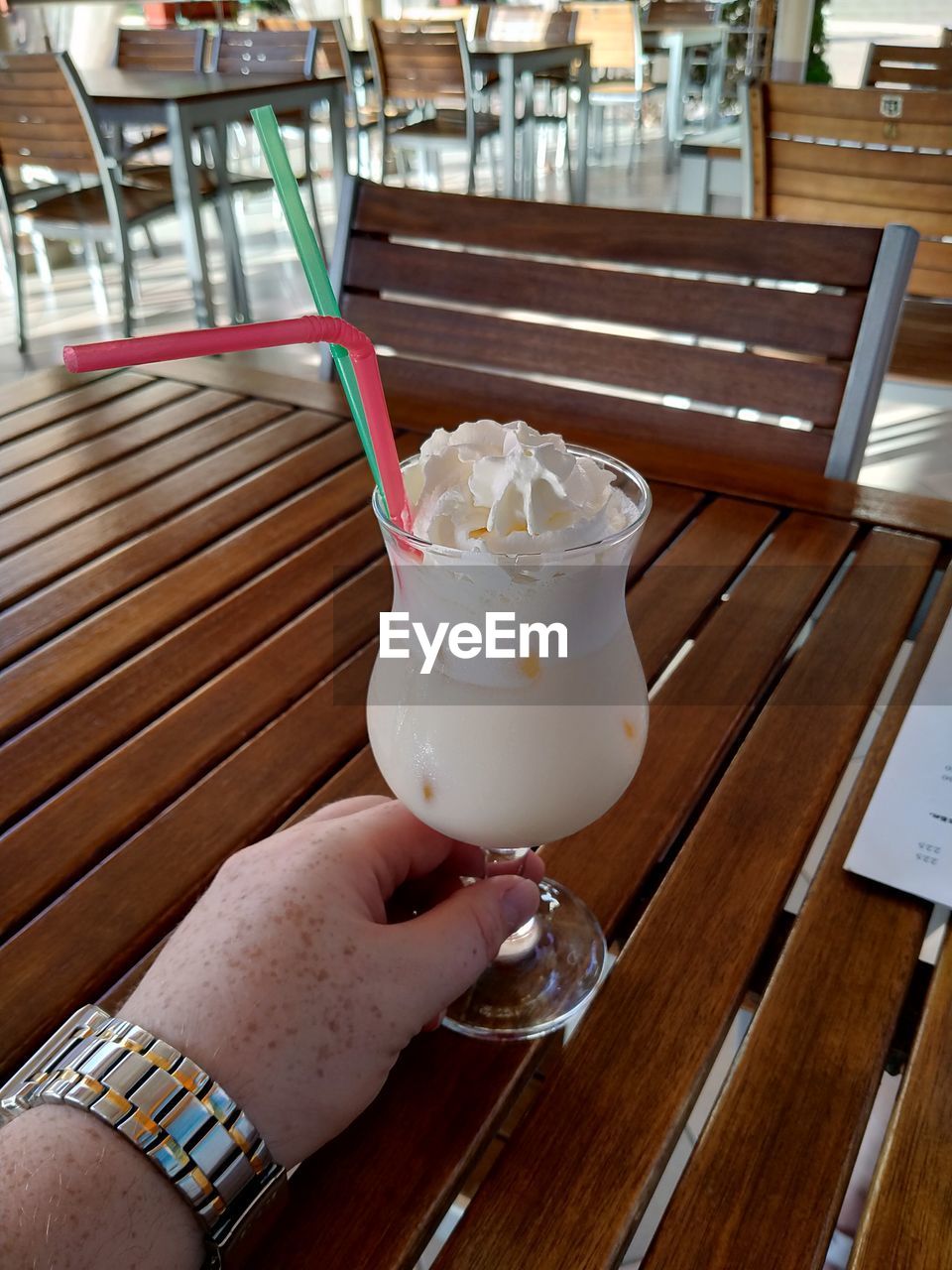 CROPPED IMAGE OF HAND HOLDING ICE CREAM WITH GLASS OF TABLE