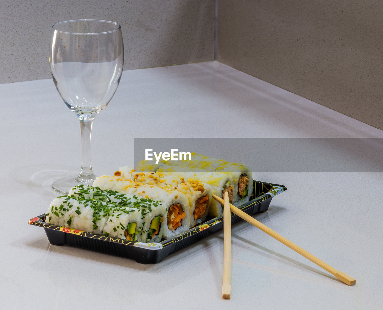 Sushi in plate by wineglass on white table