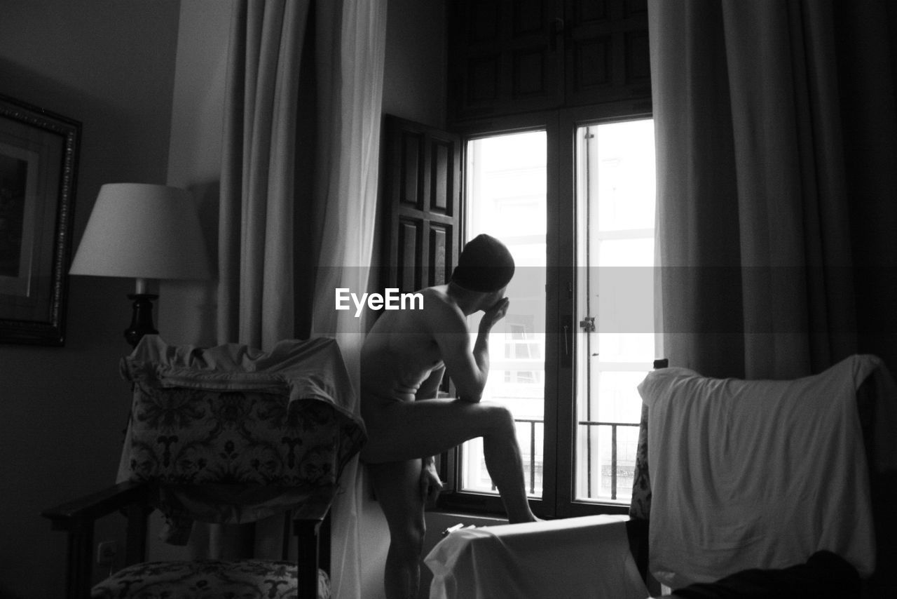 MAN SITTING ON CHAIR IN BEDROOM