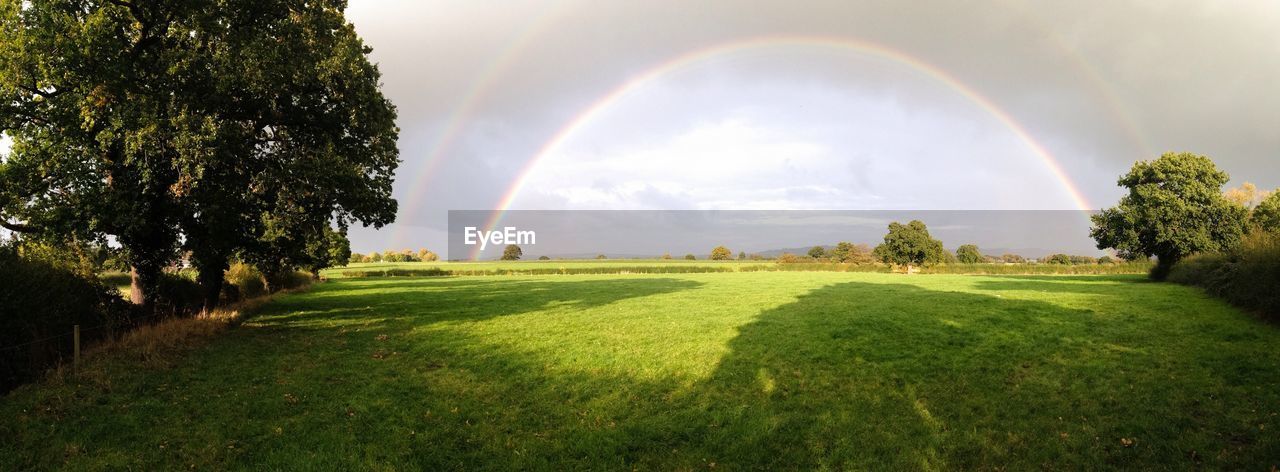 Scenic view of field against rainbow in sky