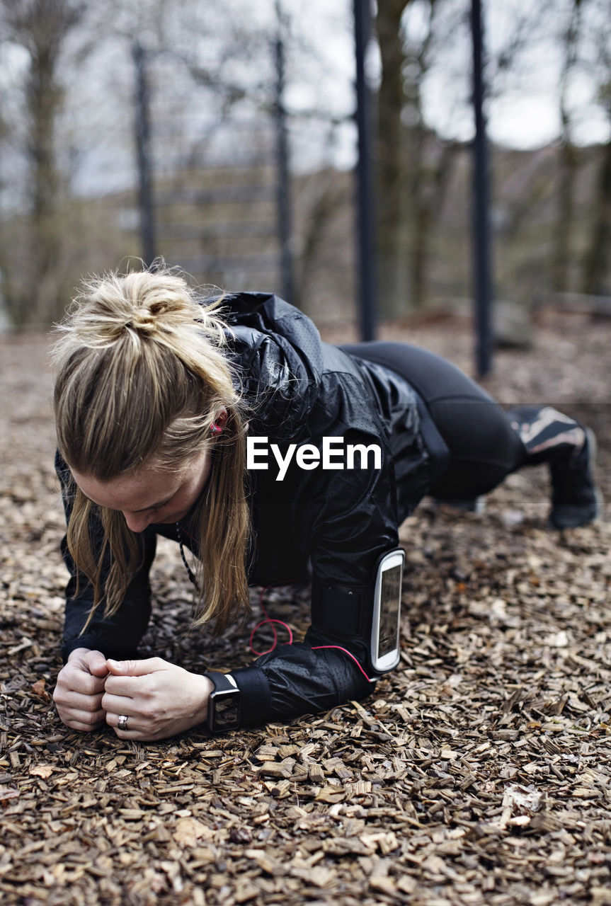 Female athlete performing plank position in forest